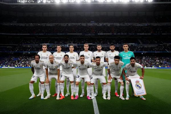 REAL MADRID Slots - Thousands of thrilling machines await A woman smiling by bright slot machines showing lucky symbols, showcasing the exciting slot offerings at REAL MADRID.